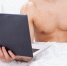 Midsection Of Shirtless Man Holding Laptop In Bed - ИА Общественная служба новостей