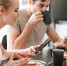 Pretty concentrated lovers using their smarrtphones while have breakfast in kitchen - ИА Общественная служба новостей